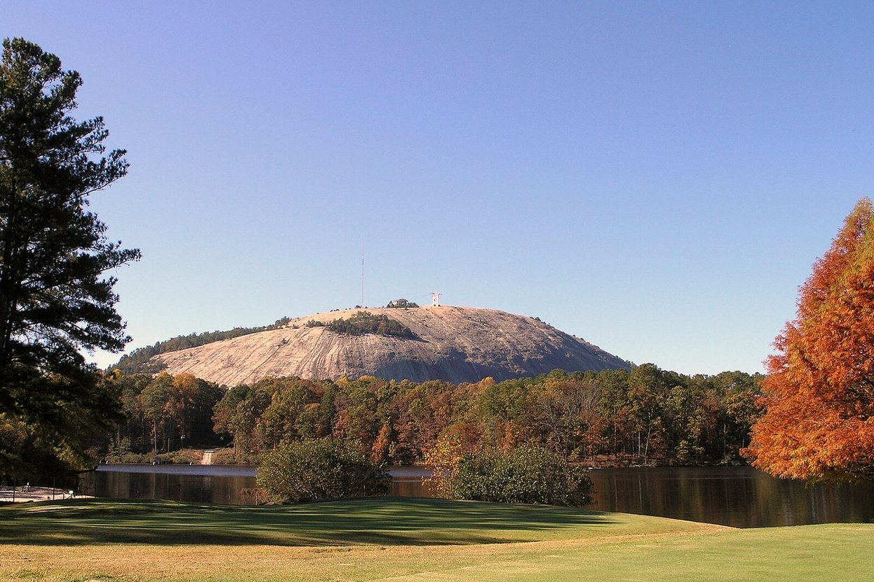 A golf course green in late fall with autumn trees