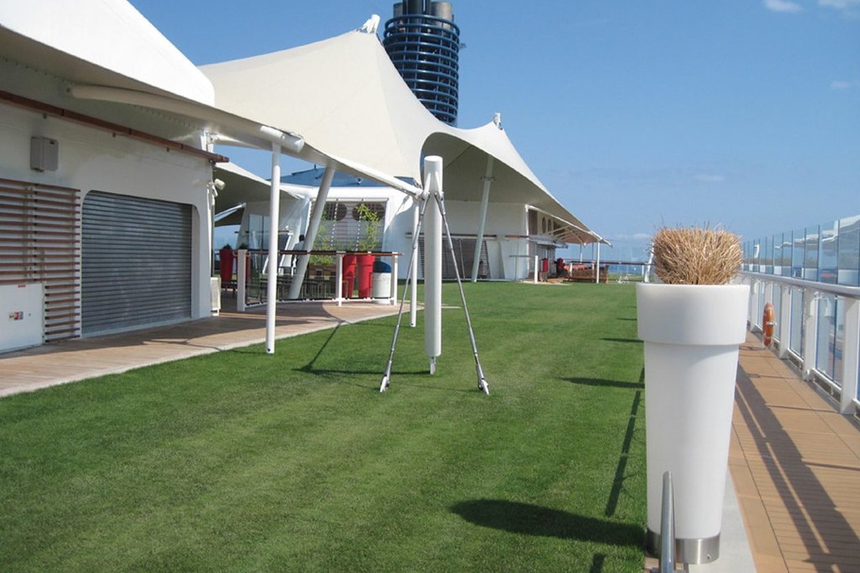 Real grass lawn on the top deck of a cruise ship, under white shade canopies